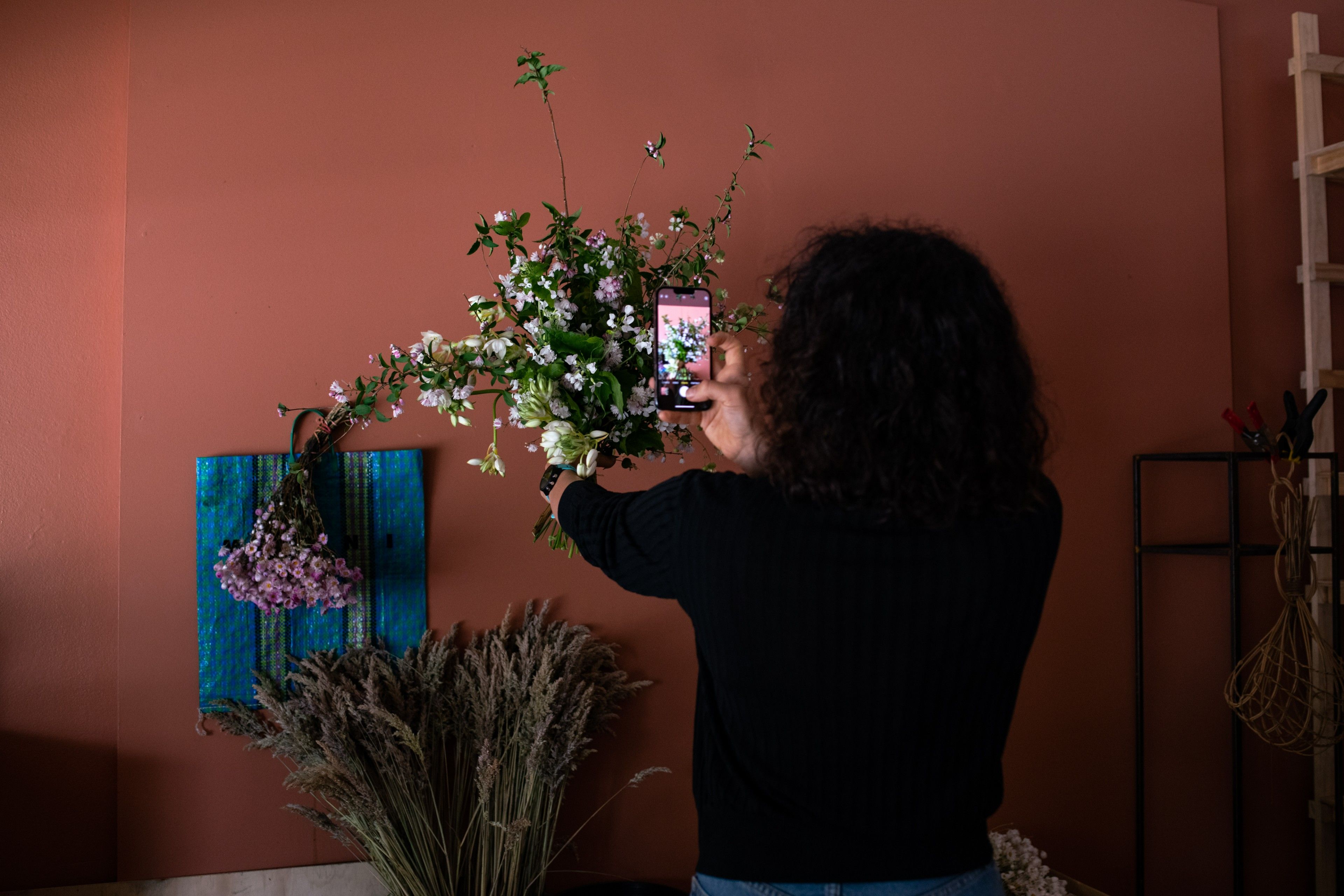 e コマース サイトに掲載する花の写真を撮っている花屋の経営者。