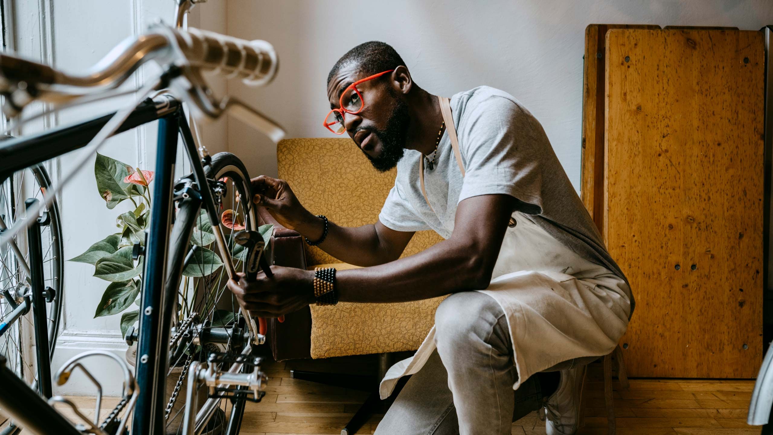 自転車を整備する、赤い眼鏡をかけた男性