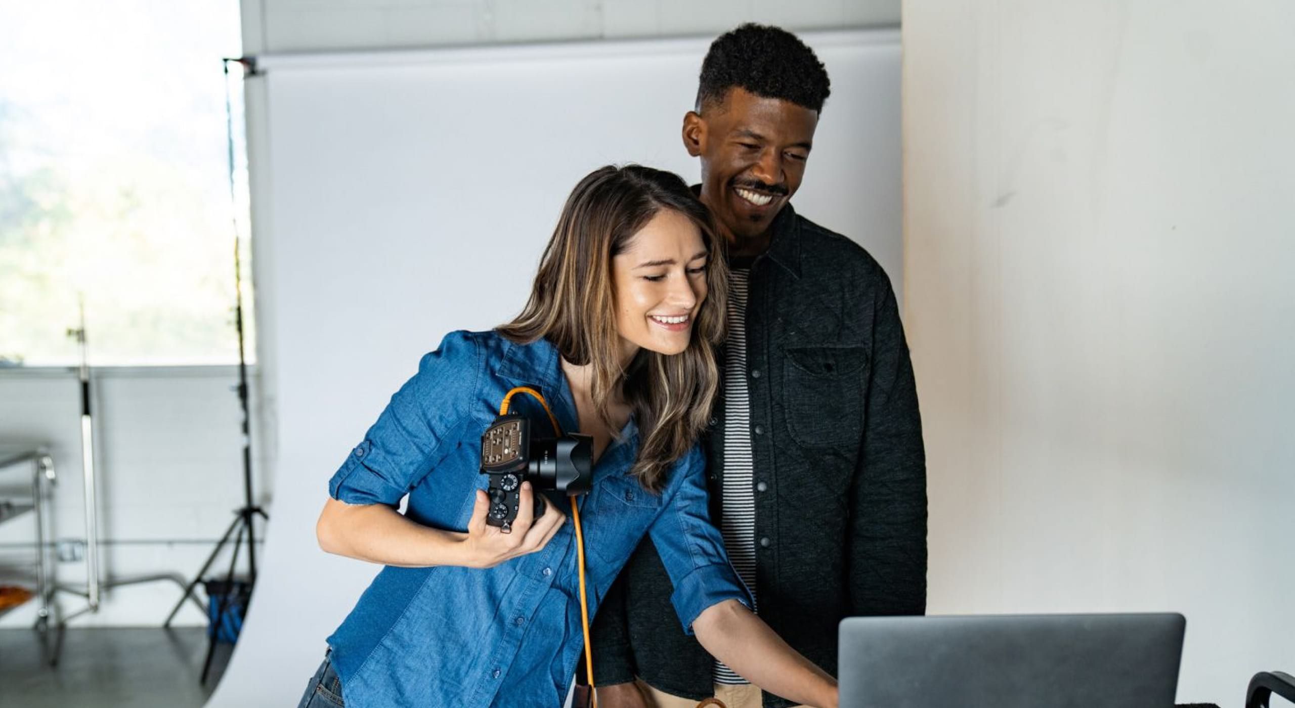 Un uomo e una donna che guardano delle immagini scattate con una fotocamera digitale su un computer portatile