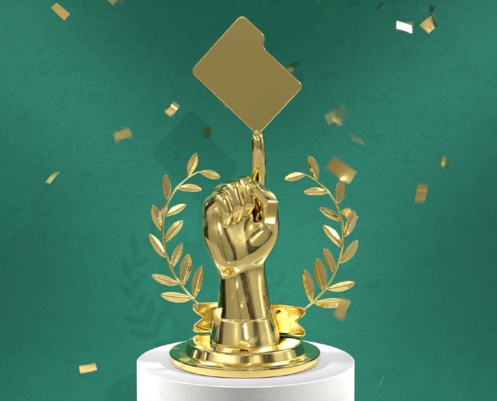 Gouden trofee van een gebalde vuist met een uitgestrekte wijsvinger die een map in evenwicht houdt