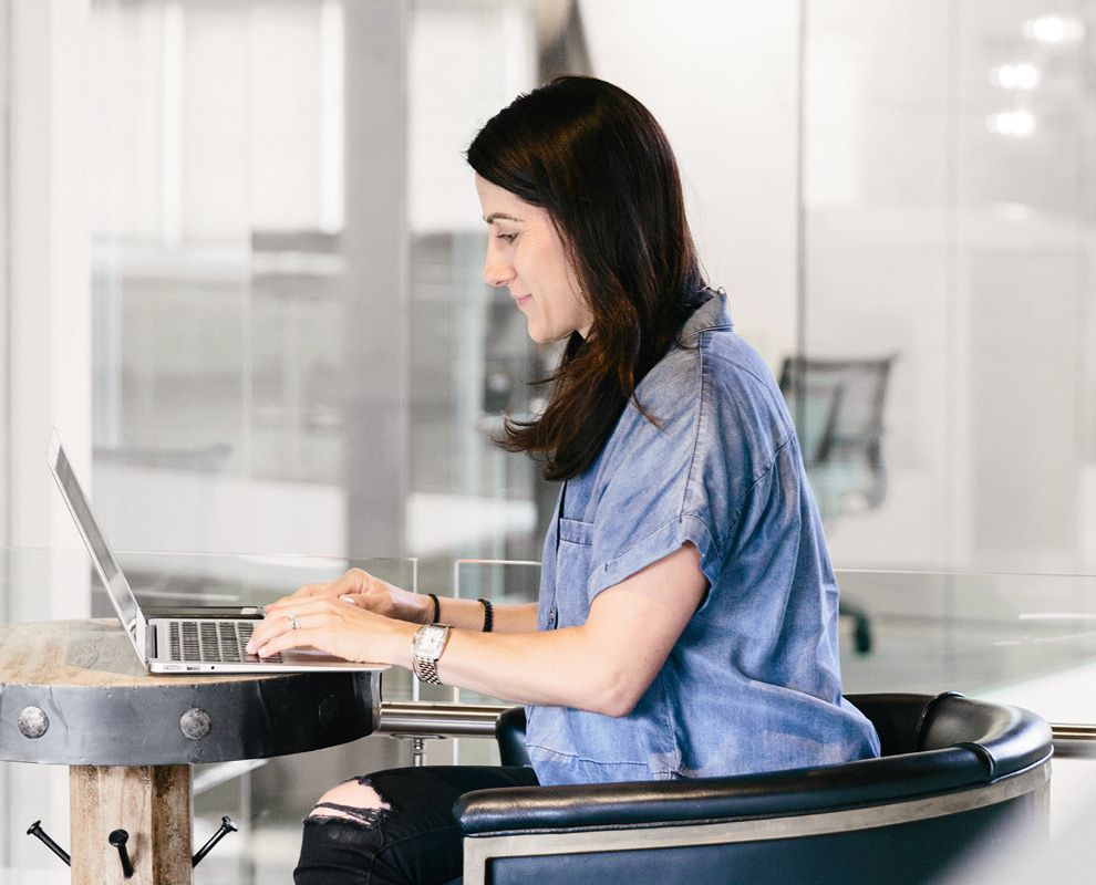 Kvinde, der arbejder ved en bærbar computer på et bord