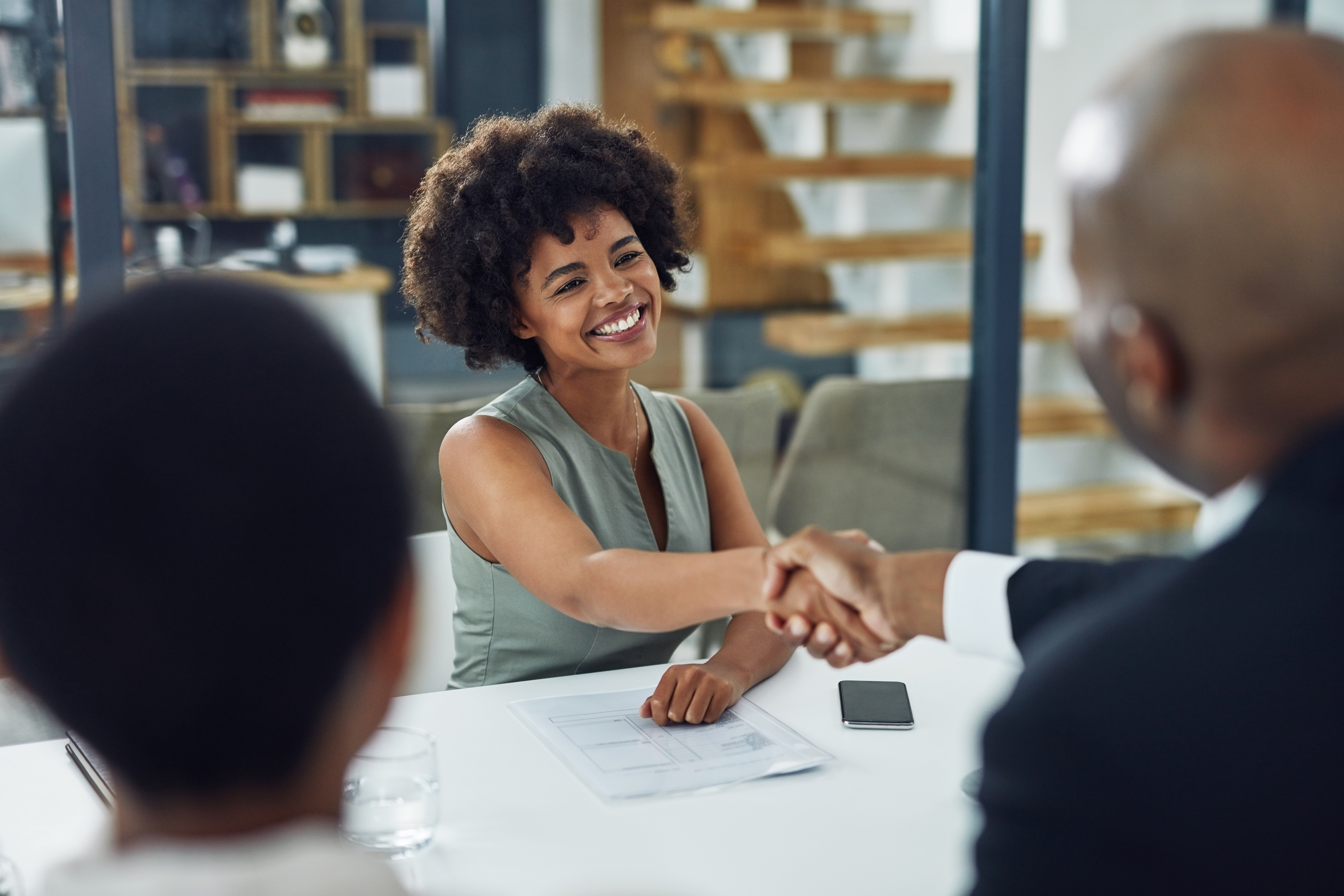  Deux employés se serrant la main sous le regard d’un autre