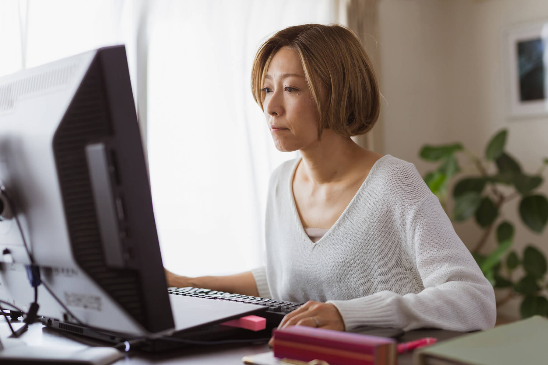 A person sits at their home desk to send a freelance writing invoice.