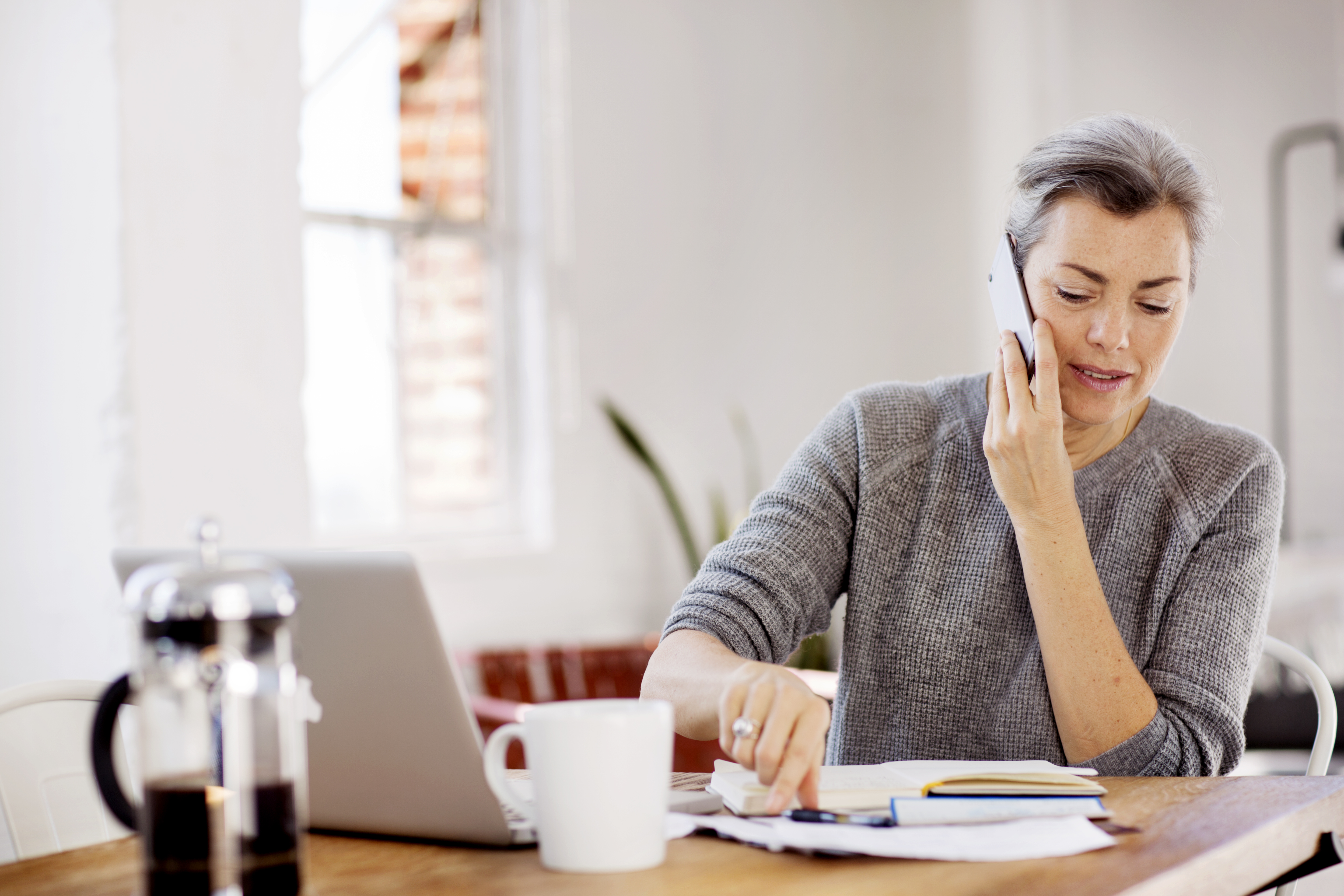 A professional speaks on the phone with their laptop open in front of them.